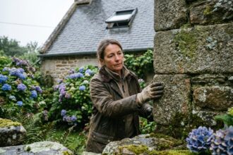 Femme inspectant un mur en pierre bretonne extérieurement